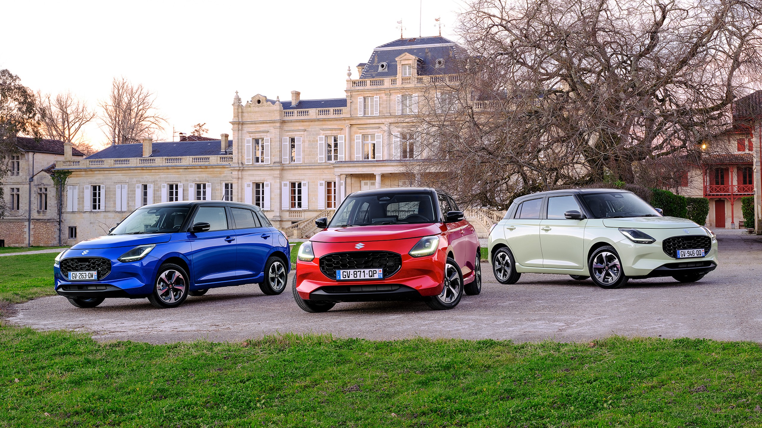 Three Suzuki Swifts parked on a gravel driveway